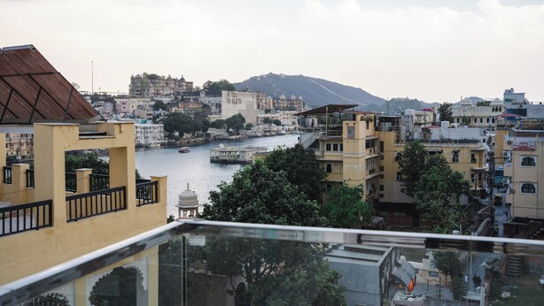 A view from a balcony overlooking a river, with buildings and a hill in the background. - Hostel Funky Bunky  (Udaipur)