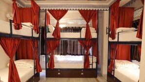 A room with bunk beds, red curtains, and a fan. - Hostel Funky Bunky  (Udaipur)