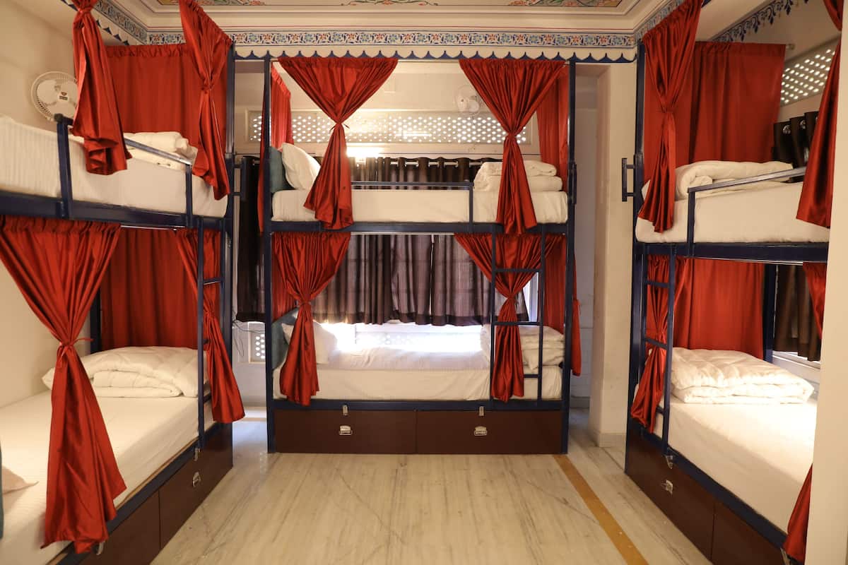 A room with bunk beds, red curtains, and a fan.
