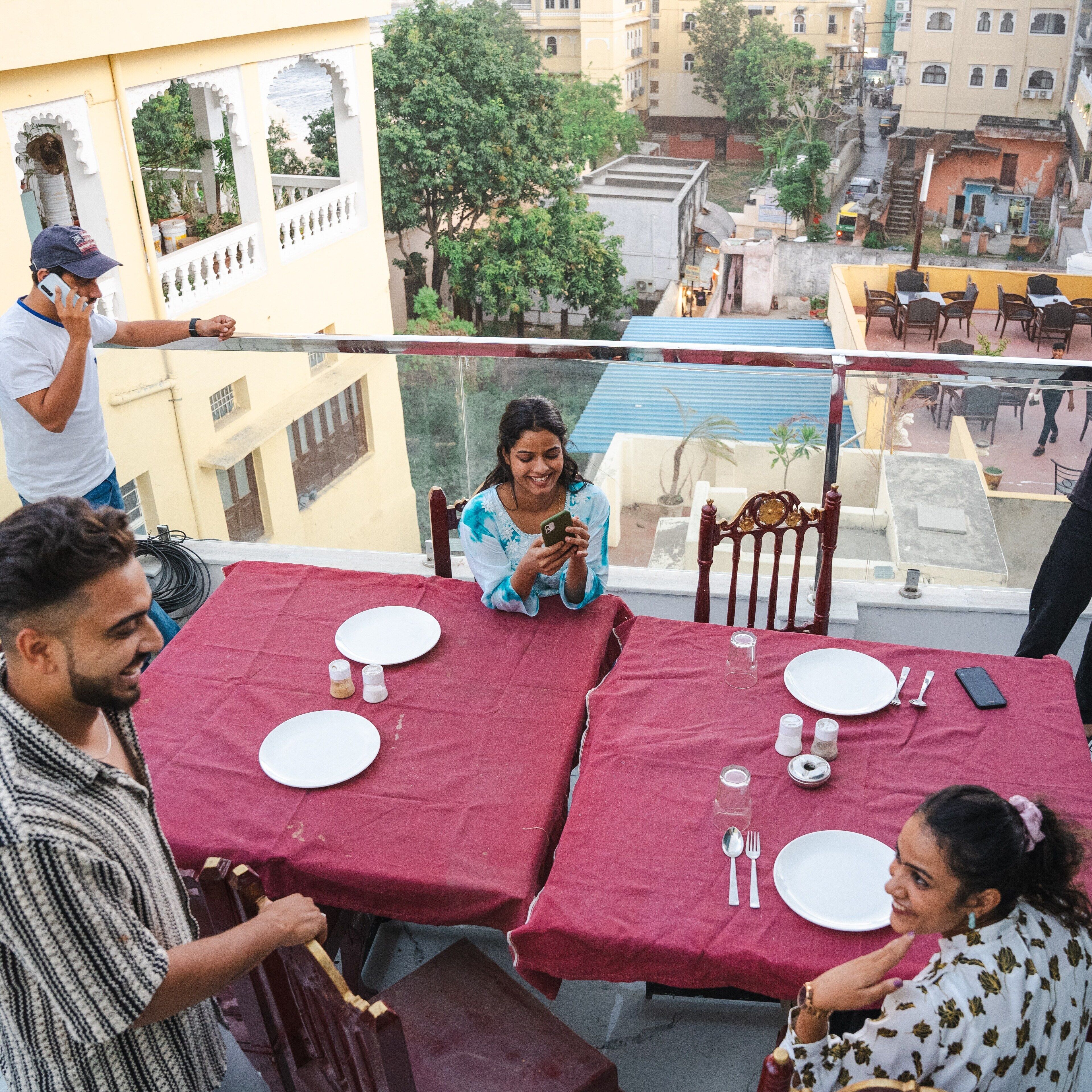 A balcony with tables set for dining, overlooking a cityscape.