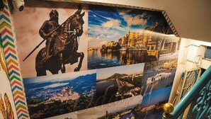 A wall with multiple photographs of historical sites and a statue of a figure on horseback. - Hostel Funky Bunky  (Udaipur)