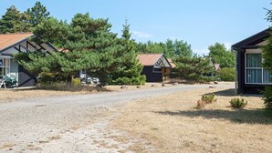 A rural property with a gravel driveway, wooden cabins, and surrounding trees. - 6 Person Holiday Home in Vaeggerlose (Vaeggerlose)