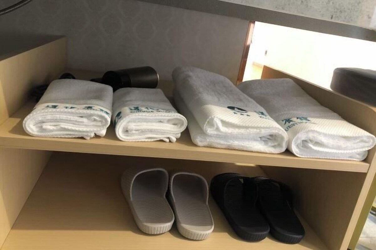 Ett hotellrum med en hylla där prydligt vikta handdukar och ett par tofflor ligger.