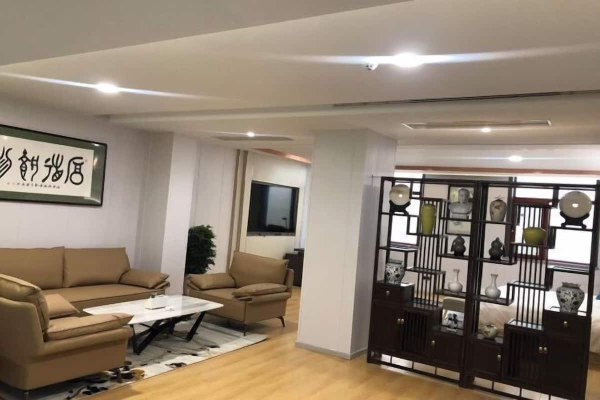 Ένα μοντέρνο σαλόνι με έναν καναπέ, μια πολυθρόνα, ένα τραπεζάκι σαλονιού και μια διακοσμητική βιτρίνα με βάζα.
