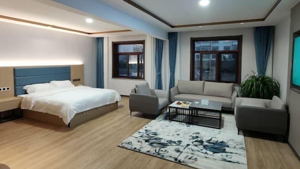 A modern hotel room with a bed, two sofas, a coffee table, and a large window. - Zunhua GuestHotel (Zunhua)