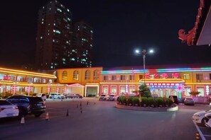 A hotel with a central courtyard, multiple floors, and illuminated signage. - Zunhua GuestHotel (Zunhua)
