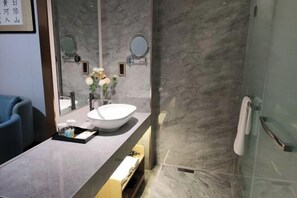Un baño moderno con un espejo grande, un lavabo blanco y una cabina de ducha de cristal.