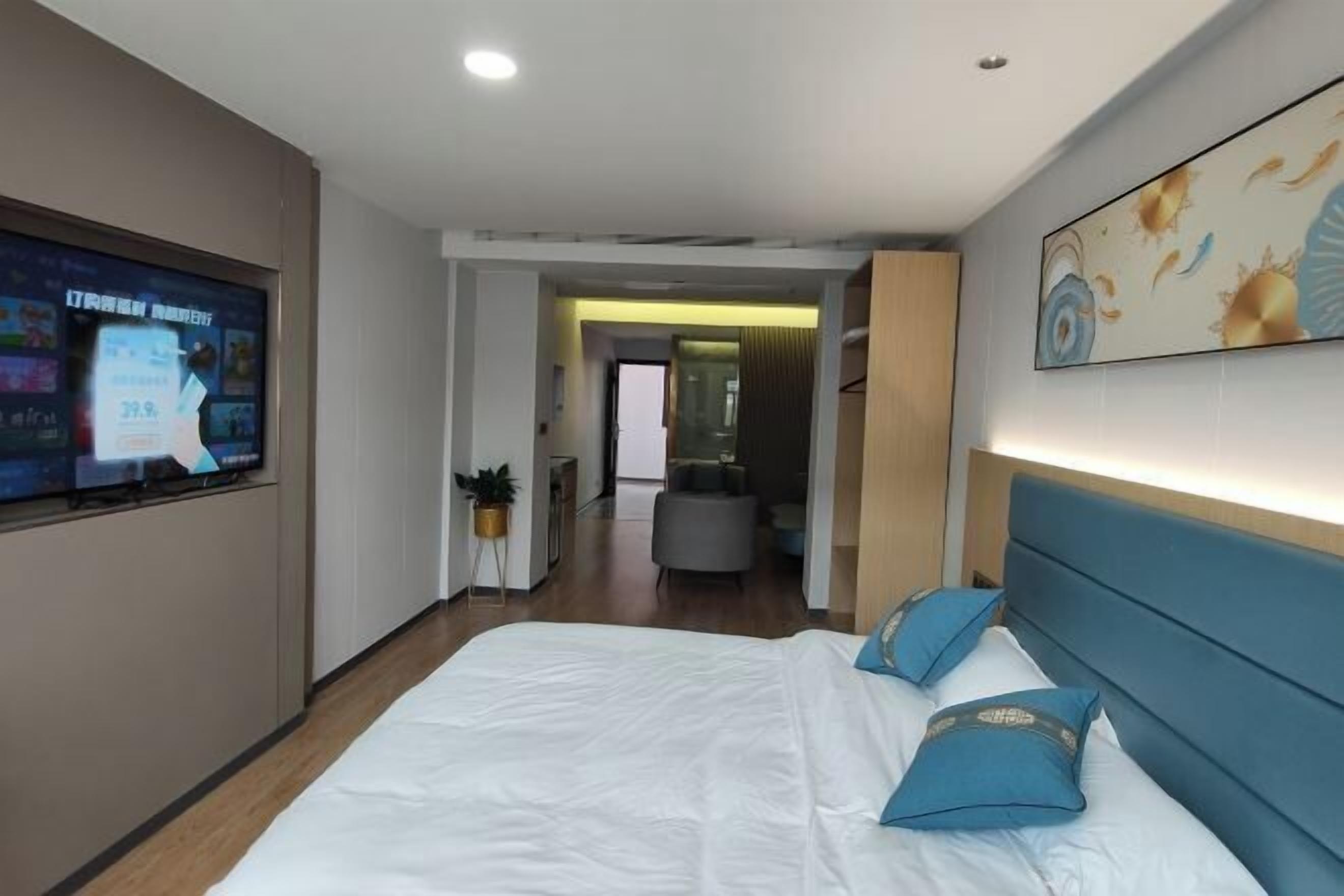 Une chambre d’hôtel avec un grand lit, un téléviseur fixé au mur et un couloir menant à la salle de bain.
