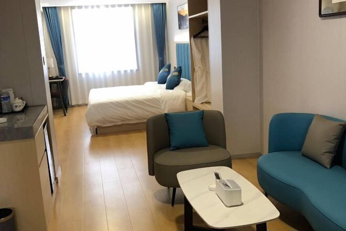 Ett hotellrum med en säng, ett skrivbord, en stol, en soffa och ett litet bord.