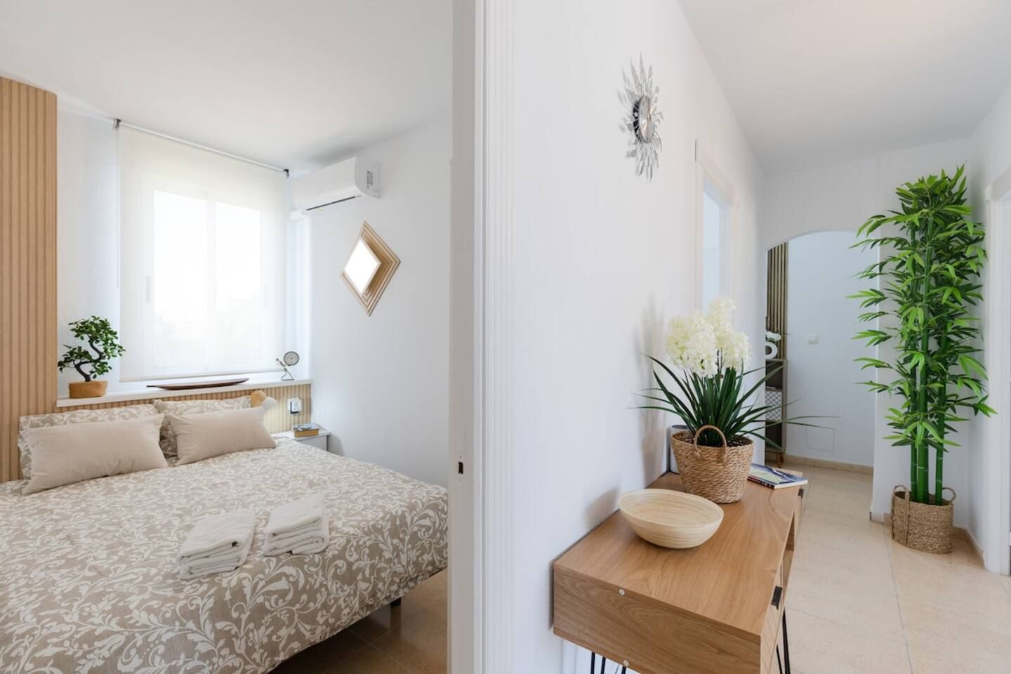 Een slaapkamer met een bed, nachtkastje en een bloempot.