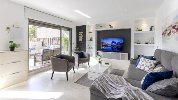 Un salon moderne avec un téléviseur à écran plat, des canapés gris et une grande fenêtre.
