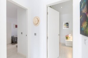 Un pasillo con una puerta que da a un dormitorio, con una cama y un sombrero colgado en la pared.