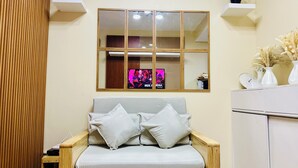 A living room with a sofa, a TV mounted on the wall, and a cabinet.