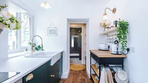 A narrow kitchen with a window, a sink, a stove, and a hanging plant. - Rufloreo Flats 1a  cosy and central (Derbyshire)