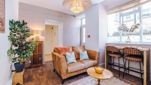A cozy living area with a leather sofa, a small round table, and a bar area with two chairs. - Rufloreo Flats 1a  cosy and central (Derbyshire)
