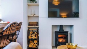 A modern living room with a fireplace, a TV mounted on the wall, and a seating area with chairs. - Rufloreo Flats 1a  cosy and central (Derbyshire)