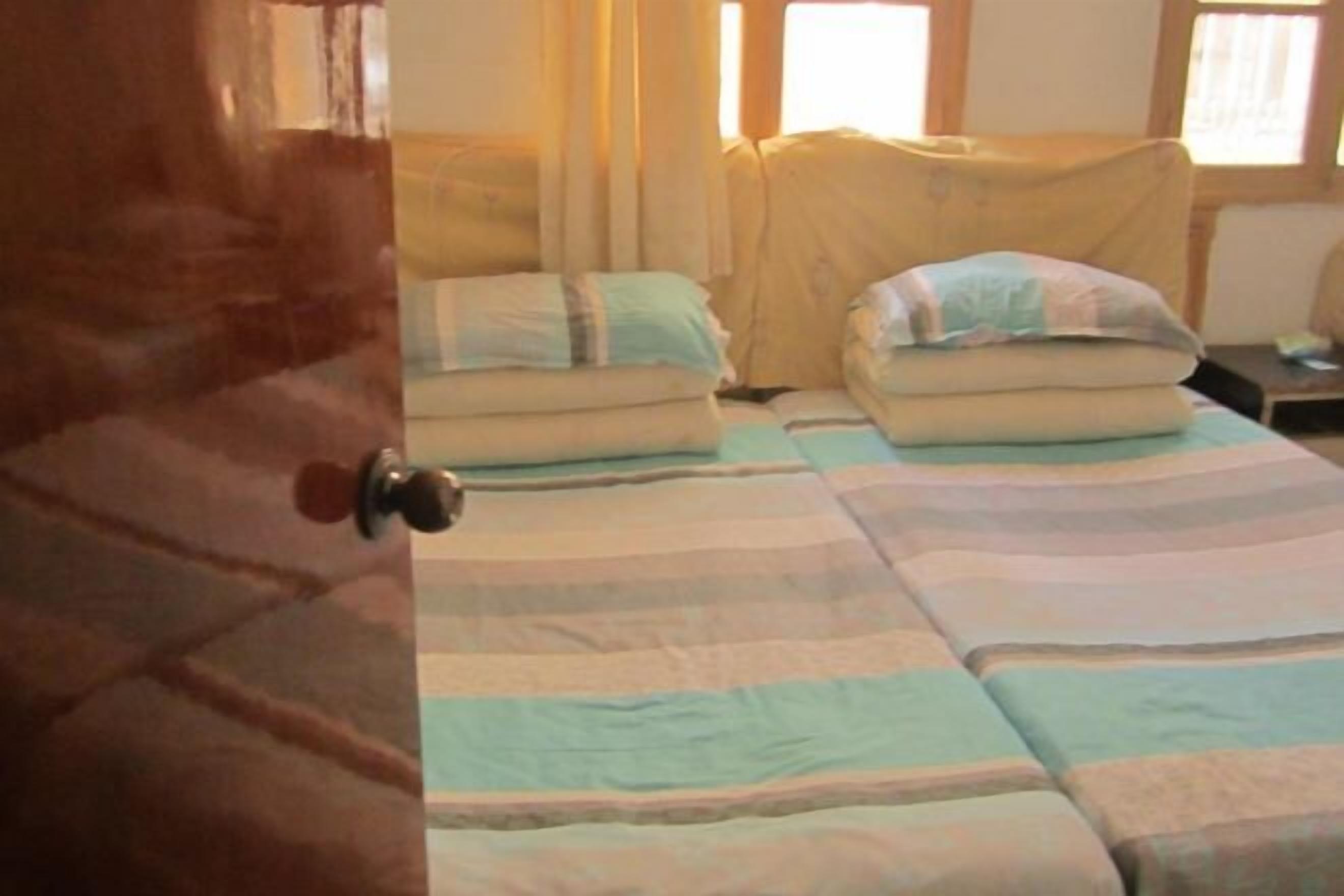 Een kamer met twee bedden, elk voorzien van gestreept beddengoed en kussens.