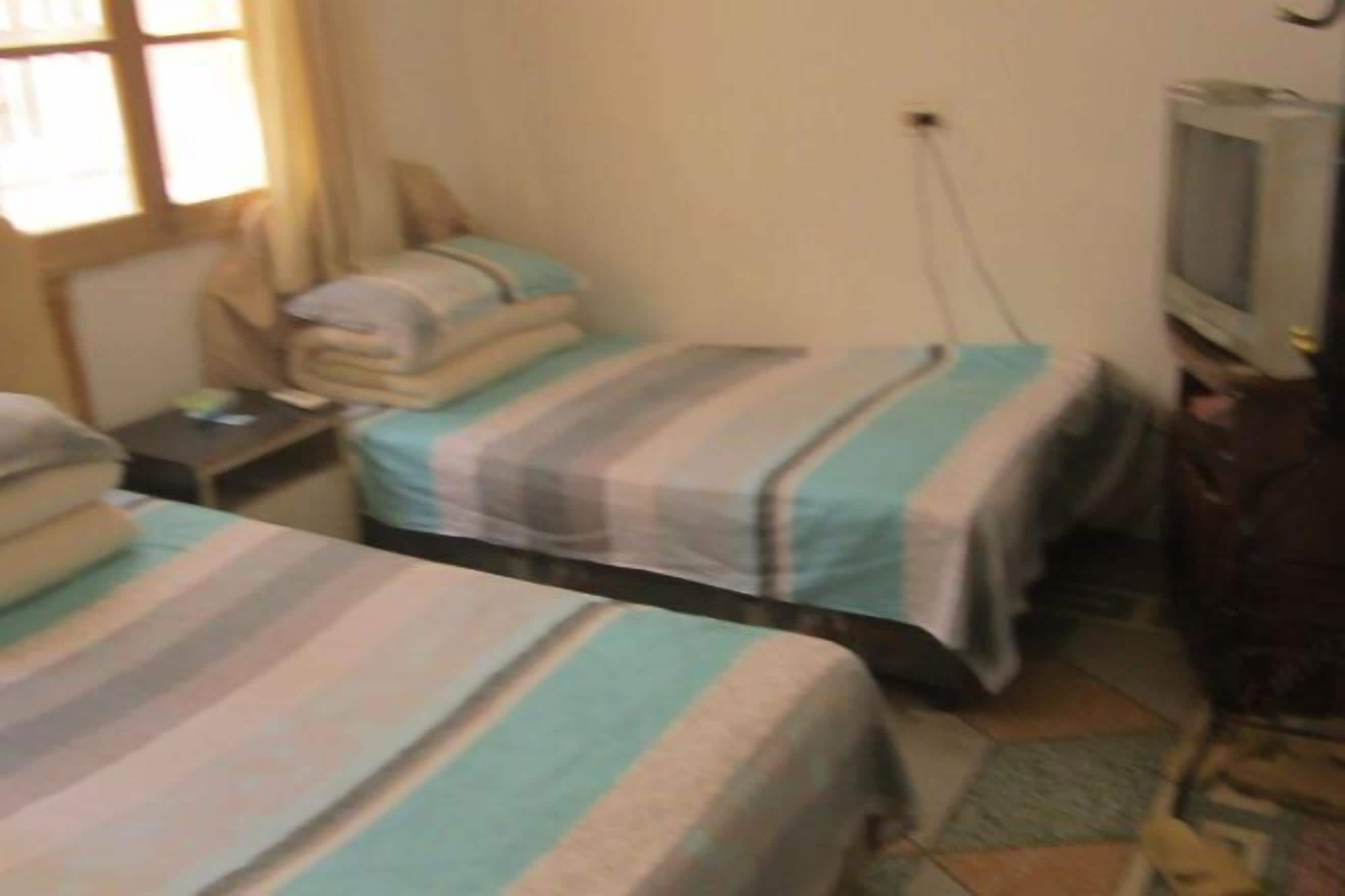 Une chambre avec deux lits, une télévision et une petite table.