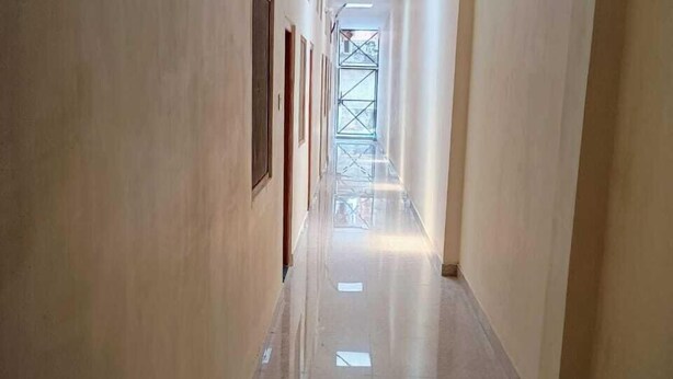 A long, narrow hallway with a shiny floor, light-colored walls, and a skylight at the end. - Ajay Palace Home Stay (Faizabad)