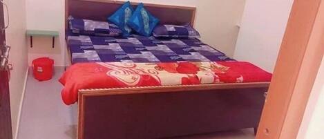 A bedroom with a wooden bed, a red and white patterned bedspread, and blue pillows.