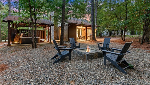 A rustic cabin with a fire pit and Adirondack chairs in a forest setting. - Pickleball, Pool, Splash Fountain ,Clubhouse , Walking Trails , Basketball (Broken Bow)