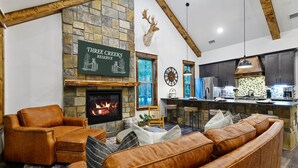 A cozy living room with a stone fireplace, leather furniture, and a mounted deer head. - Pickleball, Pool, Splash Fountain ,Clubhouse , Walking Trails , Basketball (Broken Bow)