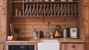A kitchen with wooden cabinets, a sink, and various kitchen appliances including a kettle and a coffee maker. - Seaside Escape Cottage in Broadstairs (Broadstairs)
