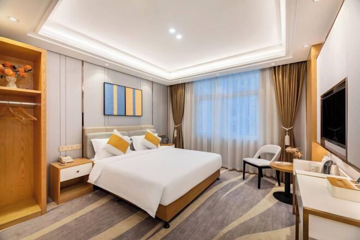 Ein Hotelzimmer mit Bett, Nachttisch, Stuhl, Schreibtisch und Fernseher.
