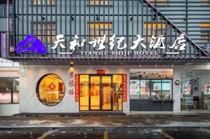 Exterior del Hotel Tianhe Shiji, con una entrada destacada, un amplio ventanal circular y una zona visible de restaurante o cafetería.