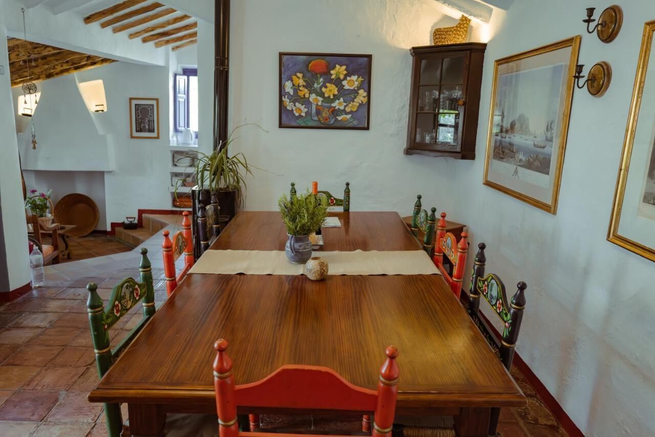 A dining room with a wooden table, chairs, and a vase of flowers.