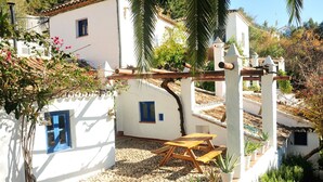 A white building with blue windows and a wooden bench in the courtyard. - Villa El Tejar - Montecorto, Serrania de Ronda, Spain (Montecorto)