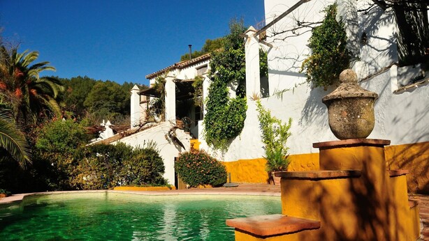 A pool area with a clear blue pool, surrounded by a white building with yellow trim and greenery. - Villa El Tejar - Montecorto, Serrania de Ronda, Spain (Montecorto)