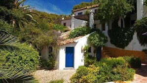 A white building with a blue door, surrounded by lush greenery and a clear blue sky. - Villa El Tejar - Montecorto, Serrania de Ronda, Spain (Montecorto)