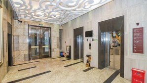 A lobby with marble flooring, two elevators, and a decorative ceiling. - Jinjiang Tianhe Grand Hotel (Jinjing People's Government) (Jinjiang)