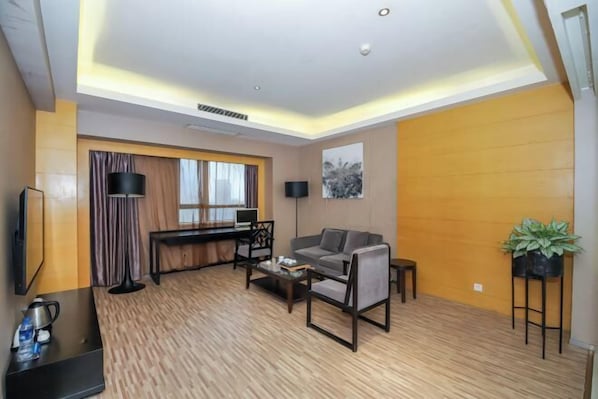 A modern living room with a sofa, coffee table, and a desk with a computer. - Jinjiang Tianhe Grand Hotel (Jinjing People's Government) (Jinjiang)