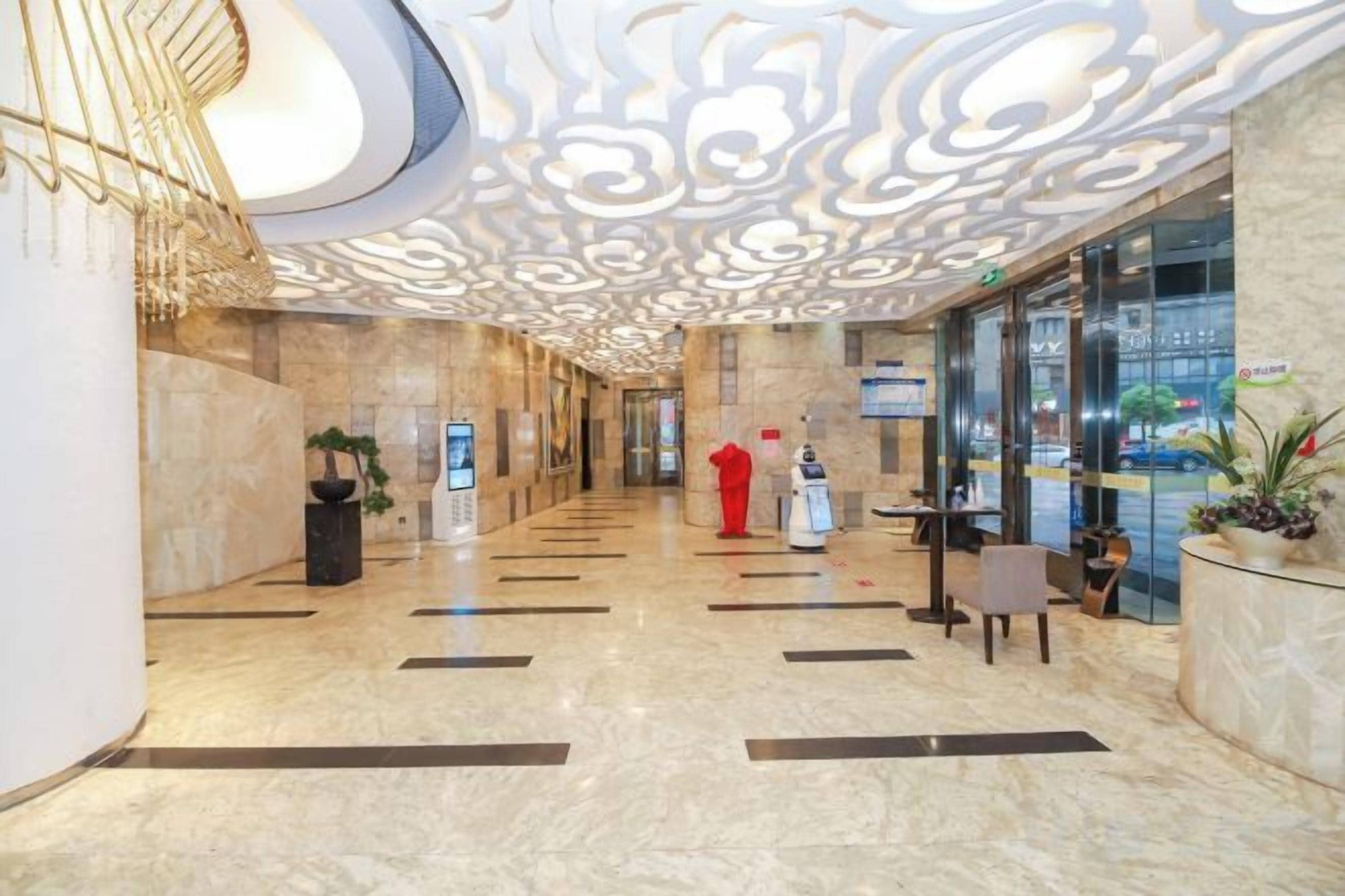 Een hotellobby met een marmeren vloer, een receptiebalie en een decoratief plafond.