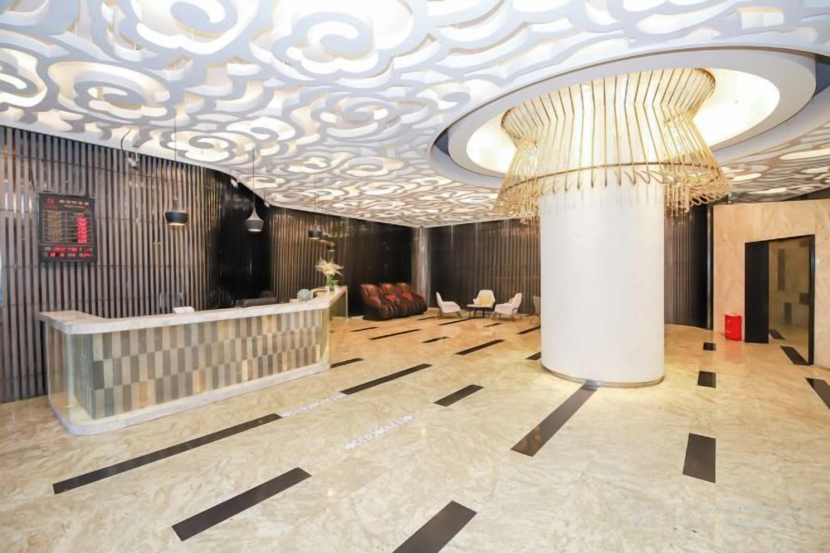 A hotel lobby with a reception desk, seating area, and a large decorative column.