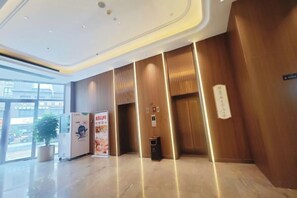 A modern lobby with a reception desk, a vending machine, and a trash bin.