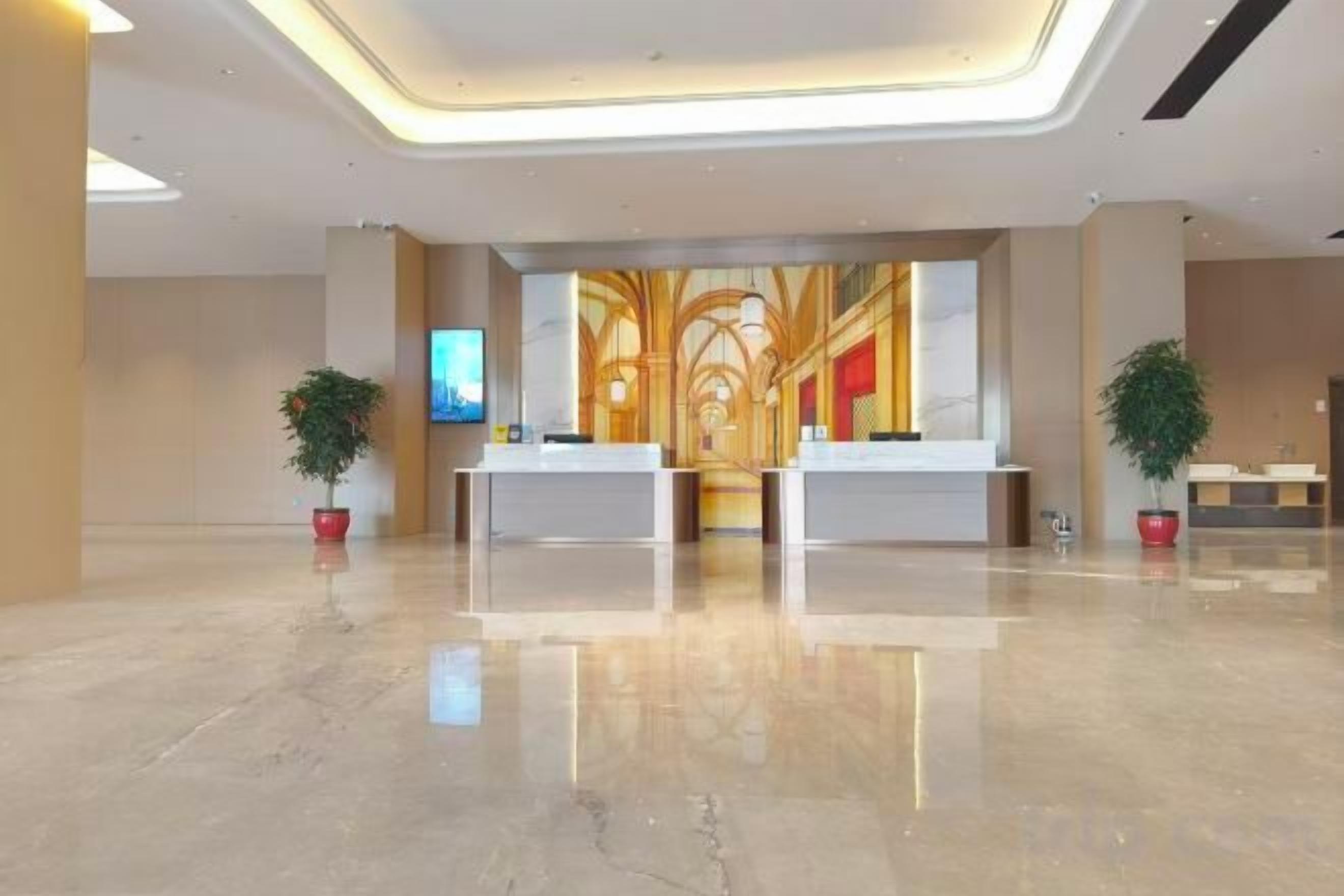 Ein Hotel-Empfangsbereich mit zwei Empfangstheken, einem großen Wandgemälde und Topfpflanzen.