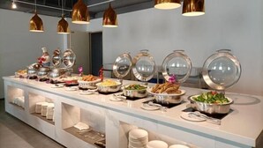 A buffet setup with various food items and serving dishes, arranged on a long table with overhead copper pendant lighting. - Jinjiang Tianhe Grand Hotel (Jinjing People's Government) (Jinjiang)