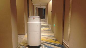A hotel hallway with a trash can, carpeted floor, and doors on both sides.