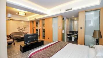 Ein Hotelzimmer mit einem großen Bett, einem Fernseher, einer Couch und einem Schreibtisch.