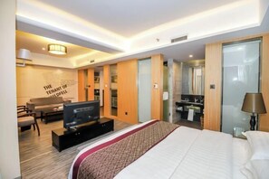 A hotel room with a large bed, a TV, a sofa, and a desk.