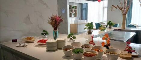 A buffet setup with various dishes and a vase of dried flowers.