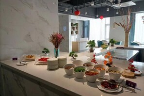 A buffet setup with various dishes and a vase of dried flowers.