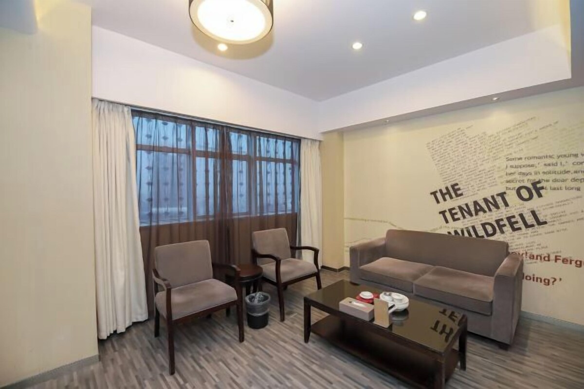 A modern living room with a sofa, two armchairs, a coffee table, and a large window with curtains.