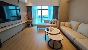 A modern living room with a flat-screen TV, two sofas, a coffee table, and a large window with curtains. - Jinjiang Tianhe Grand Hotel (Jinjing People's Government) (Jinjiang)