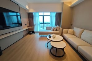 A modern living room with a flat-screen TV, two sofas, a coffee table, and a large window with curtains. - Jinjiang Tianhe Grand Hotel (Jinjing People's Government) (Jinjiang)