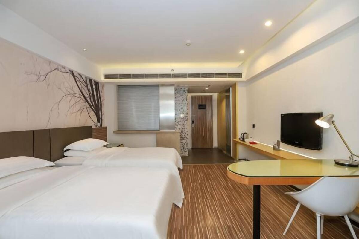 Une chambre d’hôtel avec deux lits, un bureau, une télévision et une fenêtre.