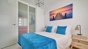 A bedroom with a bed, a nightstand, a wall-mounted painting, and a sliding door.